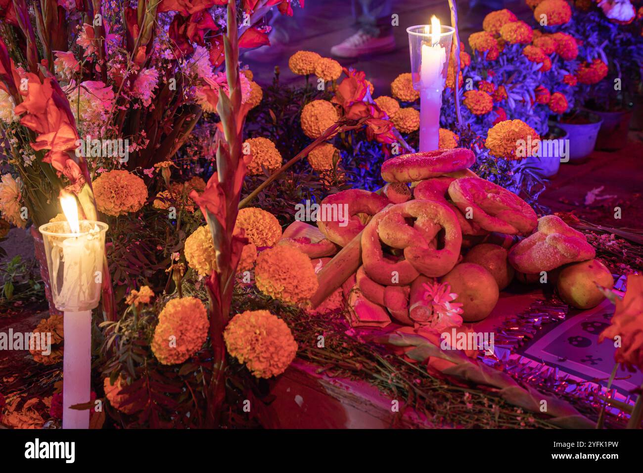 Dia de Muertos Altar mit traditionellem Brot, Ringelblumen und Kerzen, symbolisiert Opfer, um verstorbene Seelen zu ehren. Beleuchtete Ofrenda. Stockfoto