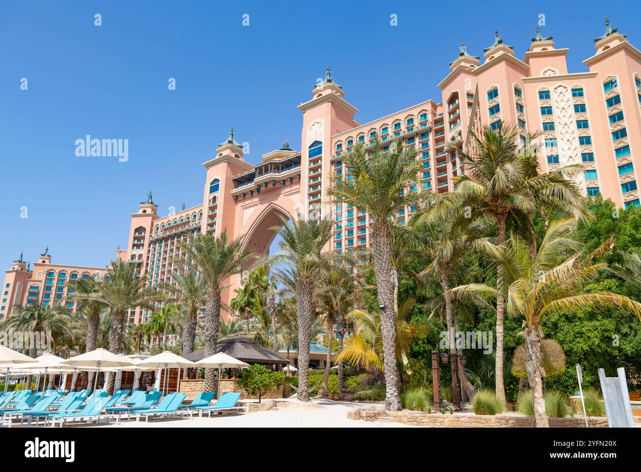 Luxuriöses Hotelresort in Dubai mit Außenfassade, Palmen im Garten und Sonnenliegen am Strand. Stockfoto