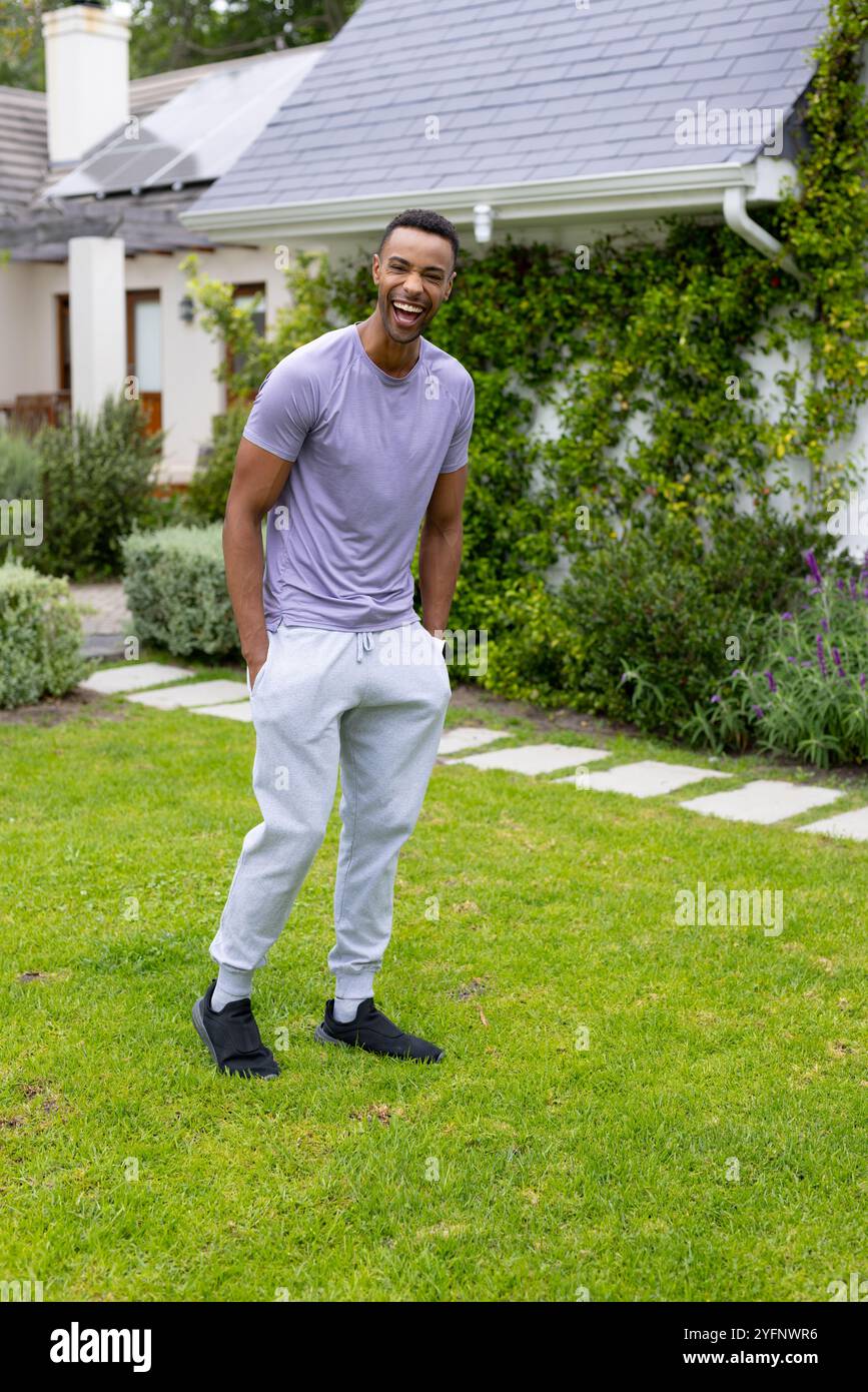 Ein lächelnder junger afroamerikaner genießt einen sonnigen Tag im Freien in legeren Outfits Stockfoto