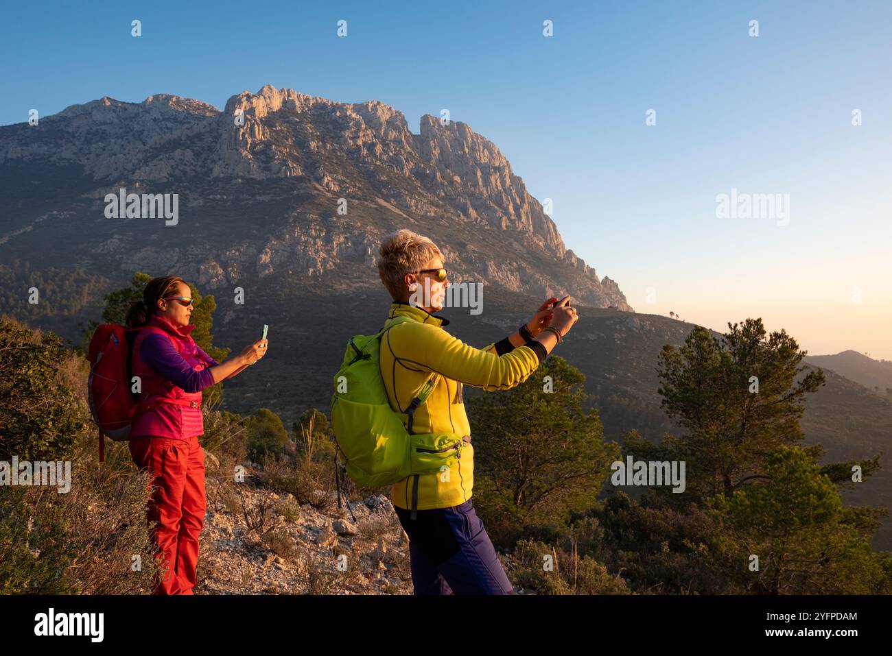 Zwei junge Frauen wandern in den Bergen und machen Fotos bei Sonnenuntergang, Sella-Tal, Provinz Alicante, Spanien - Stockfoto Stockfoto