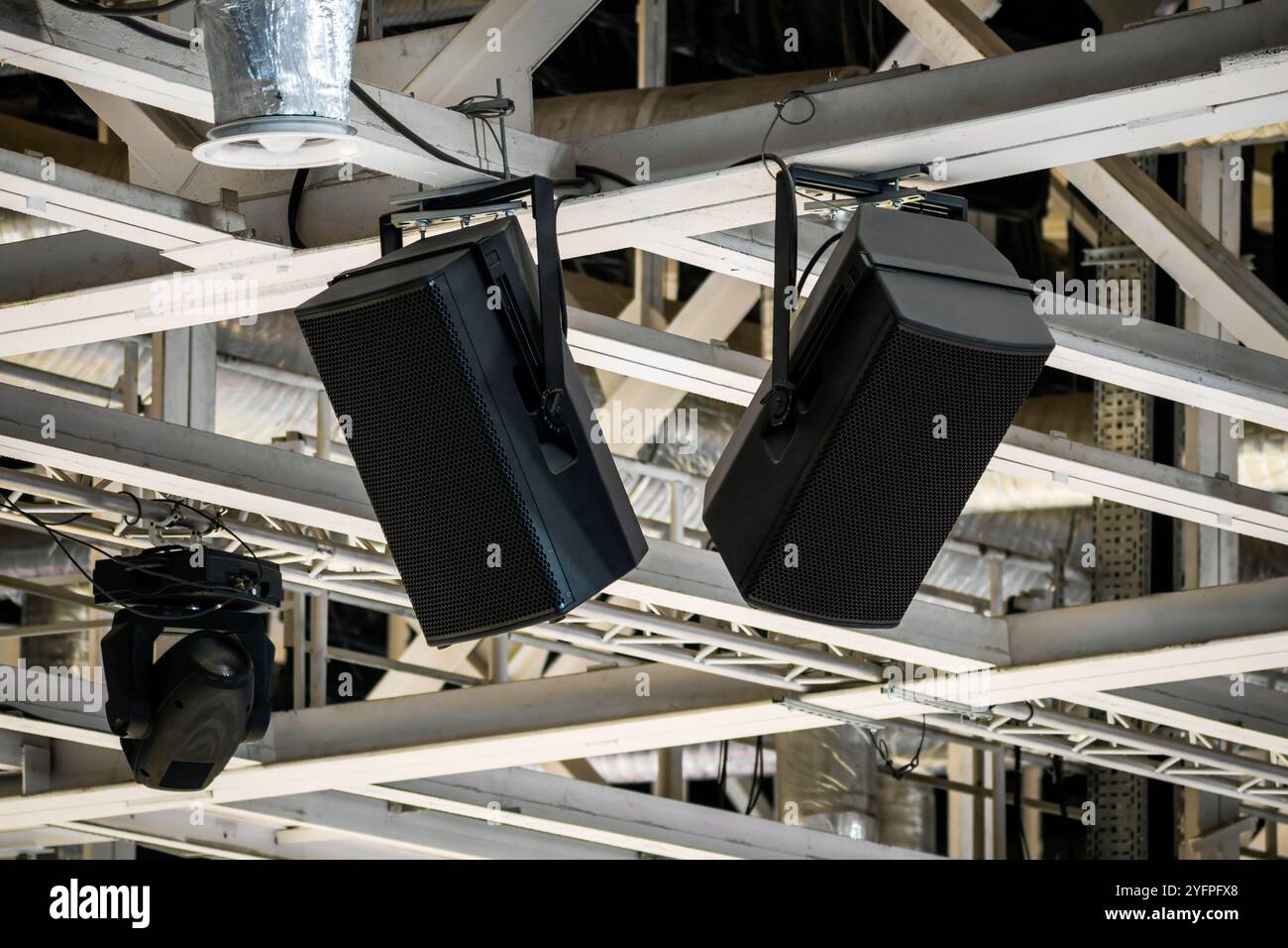 Leistungsstarke Lautsprecher, die an Balken von tragenden Strukturen unter der Decke einer großen Arena aufgehängt sind Stockfoto