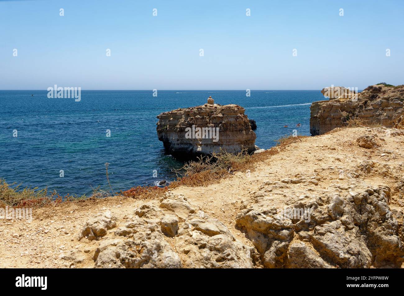 Blick auf die Küste von den Klippen von Praia de São Rafael, mit zerklüfteten Felsen und dem blauen Wasser der Algarve, das sich bis zum Horizont erstreckt Stockfoto