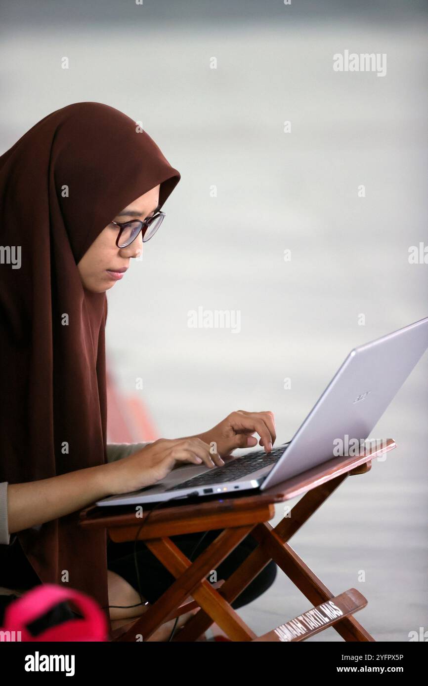 Al Akbar Surabaya Nationalmoschee. Muslimisches Mädchen, das einen Laptop benutzt, um den Koran zu lernen. Surabaya. Indonesien. Stockfoto