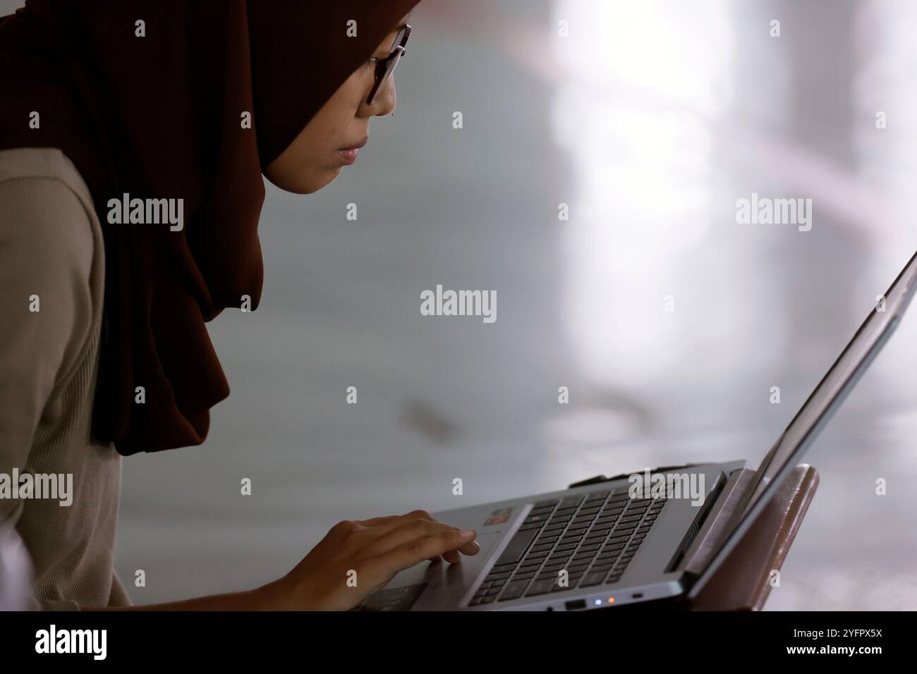 Al Akbar Surabaya Nationalmoschee. Muslimisches Mädchen, das einen Laptop benutzt, um den Koran zu lernen. Surabaya. Indonesien. Stockfoto