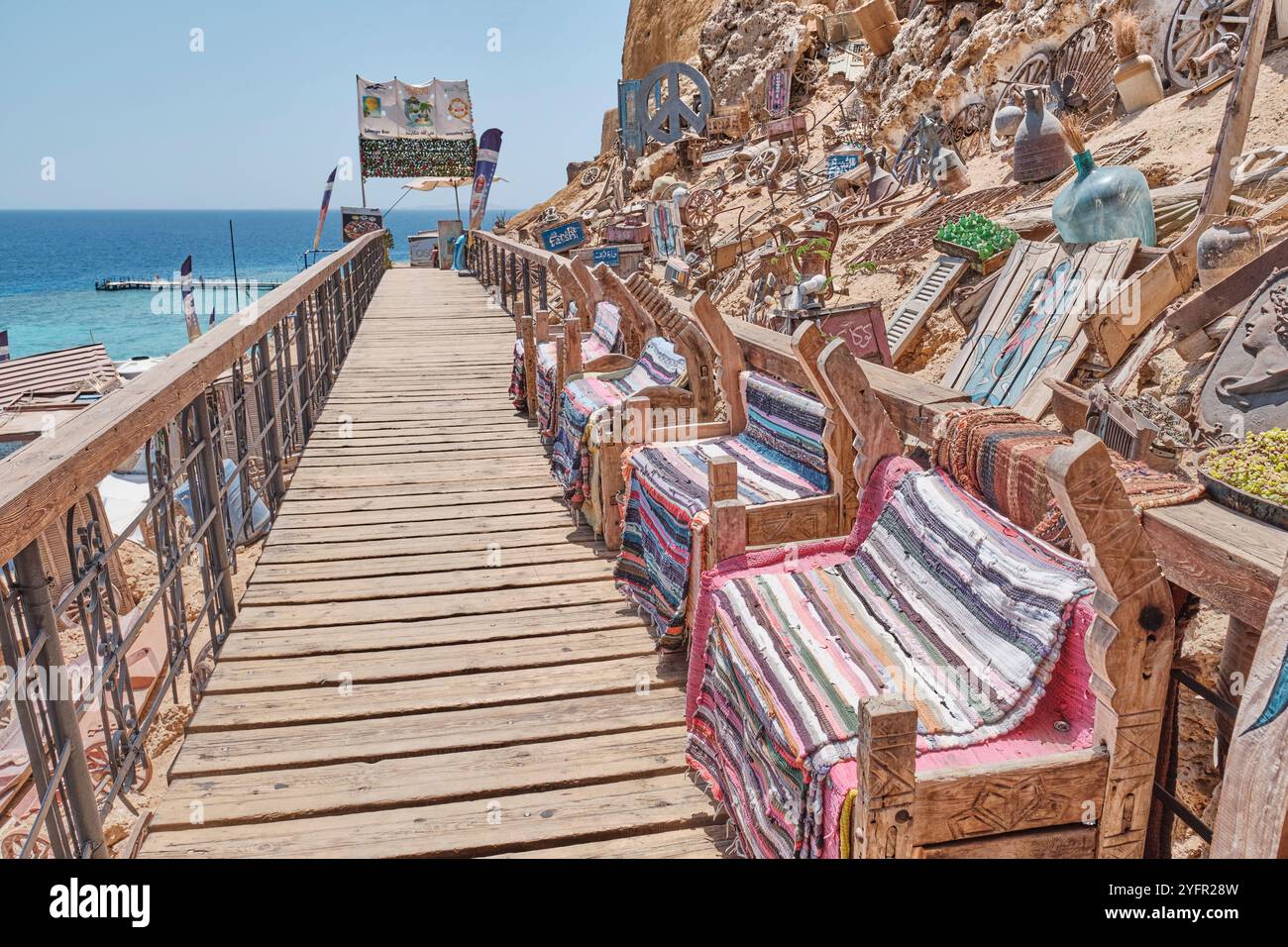 Sharm El Sheikh, Ägypten - 30. April 2024: Rustikale Holzstühle mit lebhaften gewebten Decken auf der Veranda des beliebten Farsha Cafés am Ufer des Roten Meeres in Had Stockfoto