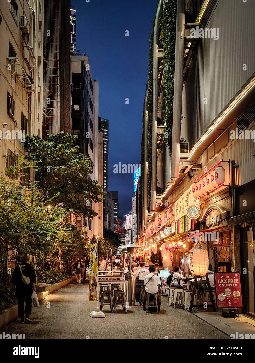 Abendessen auf einer belebten Straße in einem Stadtgebiet mit Restaurants und Lichtern der Stadt Stockfoto