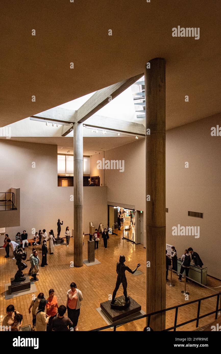 Besucher erkunden eine Kunstgalerie mit Skulpturen und natürlichem Licht in einem modernen architektonischen Raum Stockfoto