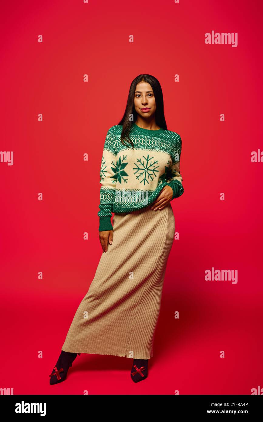 Eine stilvolle junge Frau in festlichem Pullover und langem Rock steht selbstbewusst zur Schau. Stockfoto