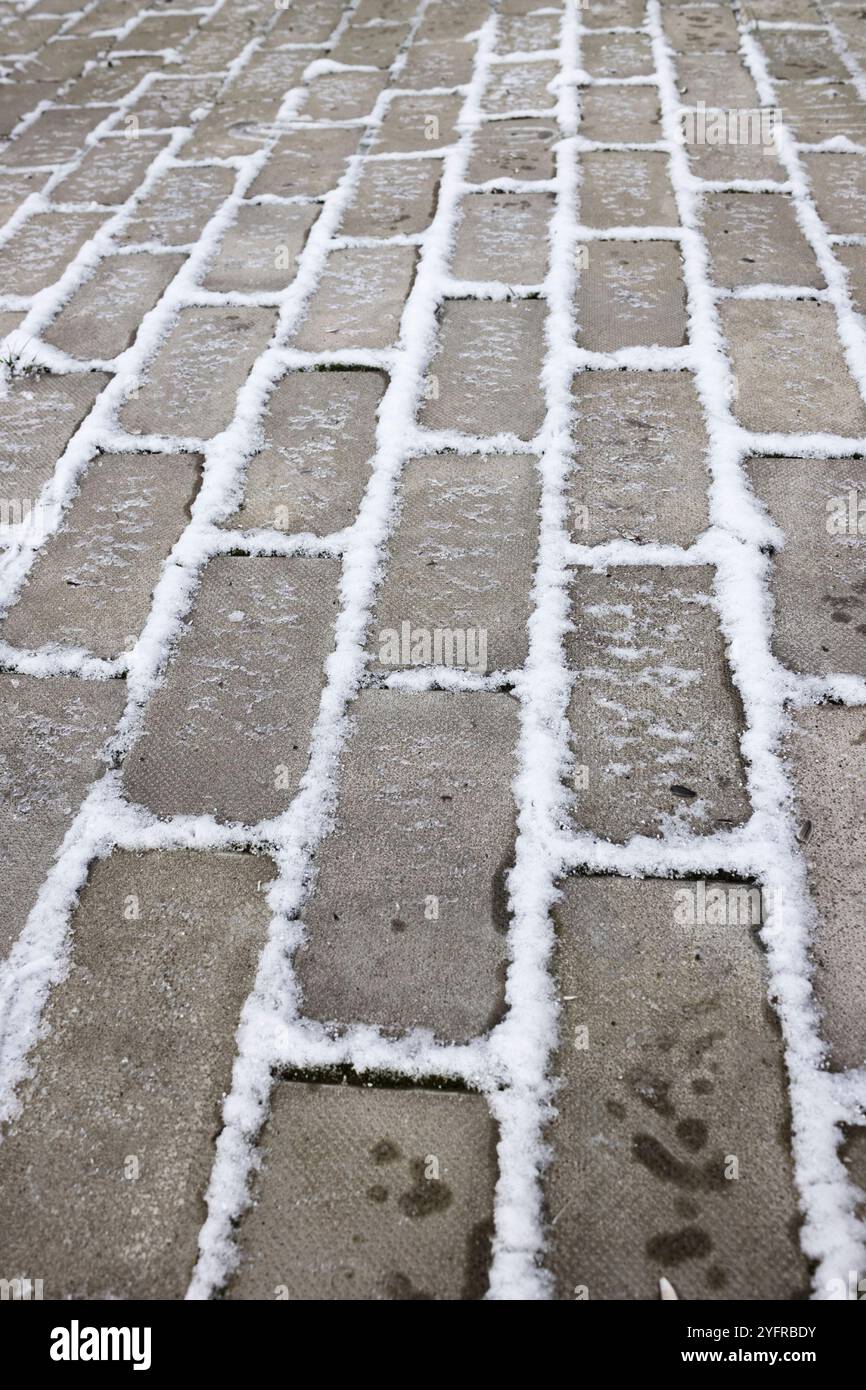 Steinweg nach Frost. Schnee in den Nähten, Eis auf der Oberfläche Stockfoto