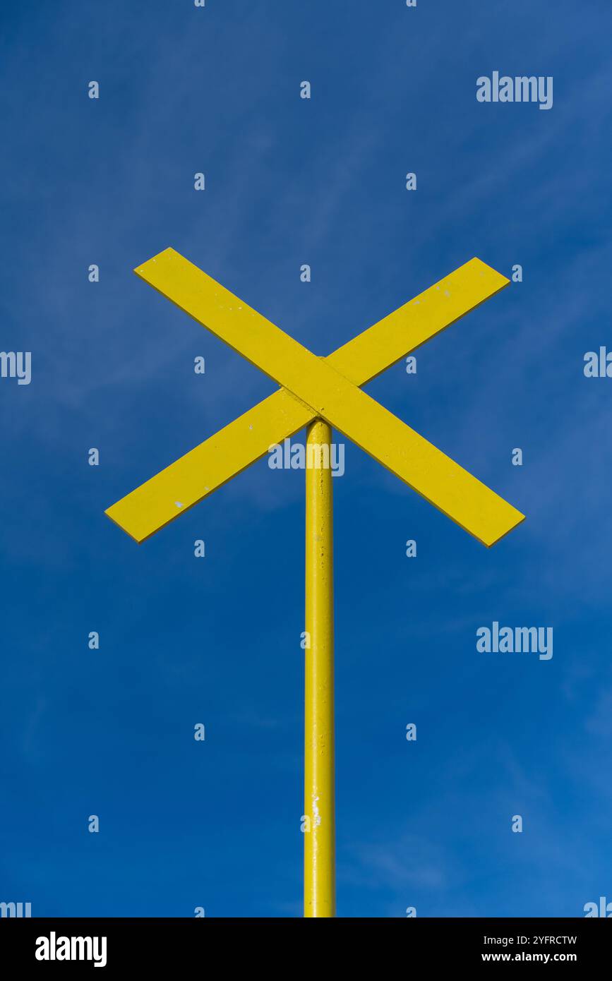 Hellgelbes Kreuzzeichen im Kontrast zum blauen Himmel. Portsmouth, Großbritannien, Oktober 2024. Stockfoto