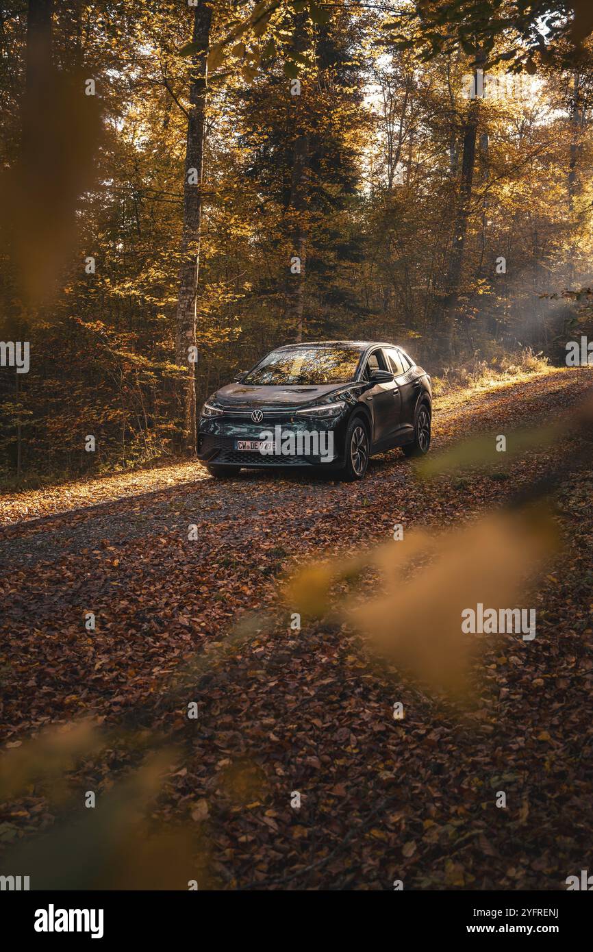 Auto auf einem grünen Weg im Herbstwald, von Sonnenlicht überflutet, Elektroauto VW ID5, Gechingen, Schwarzwald, Deutschland, Europa Stockfoto