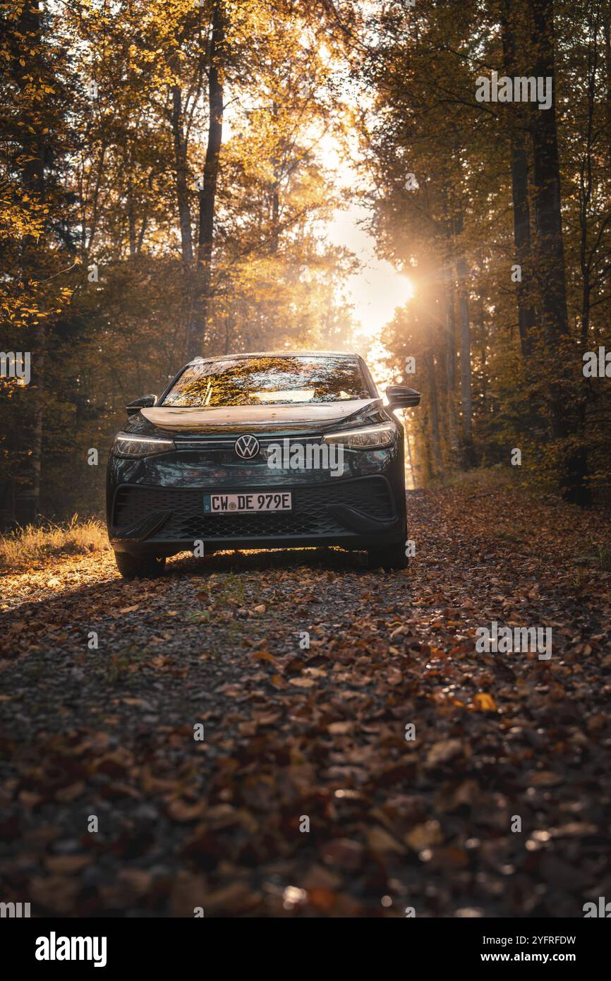 Auto auf einem Waldweg bedeckt mit Blättern in warmer Sonne, friedliche Atmosphäre, Elektroauto VW ID5, Gechingen, Schwarzwald, Deutschland, Europa Stockfoto