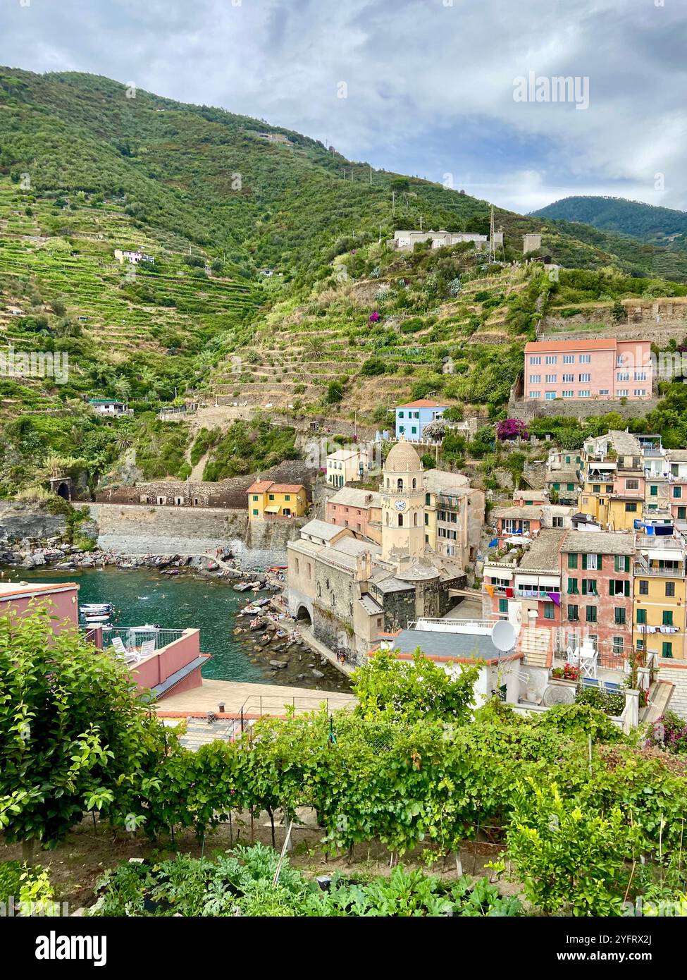 Blick auf die Weinberge, die Altstadt und die überragenden Hügel an einem bewölkten Tag in Vernazza, Cinque Terre, Ligurien, Italien Stockfoto