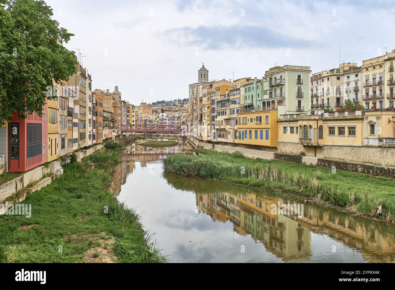 Farbenfrohe gelbe und orangefarbene Häuser und Brücke Pont de Sant Agusti spiegelten sich im Fluss Onyar in Girona, Katalonien, Spanien, wider. Kirche von Sant Feliu und Stockfoto