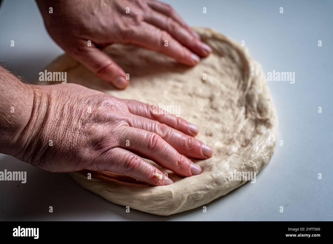 Die Hände des Pizzamakers oder Küchenchefs machen einen Kreis aus Teig für die Pizzabasis. Der Prozess der Pizza. Hochwertige Fotos Stockfoto