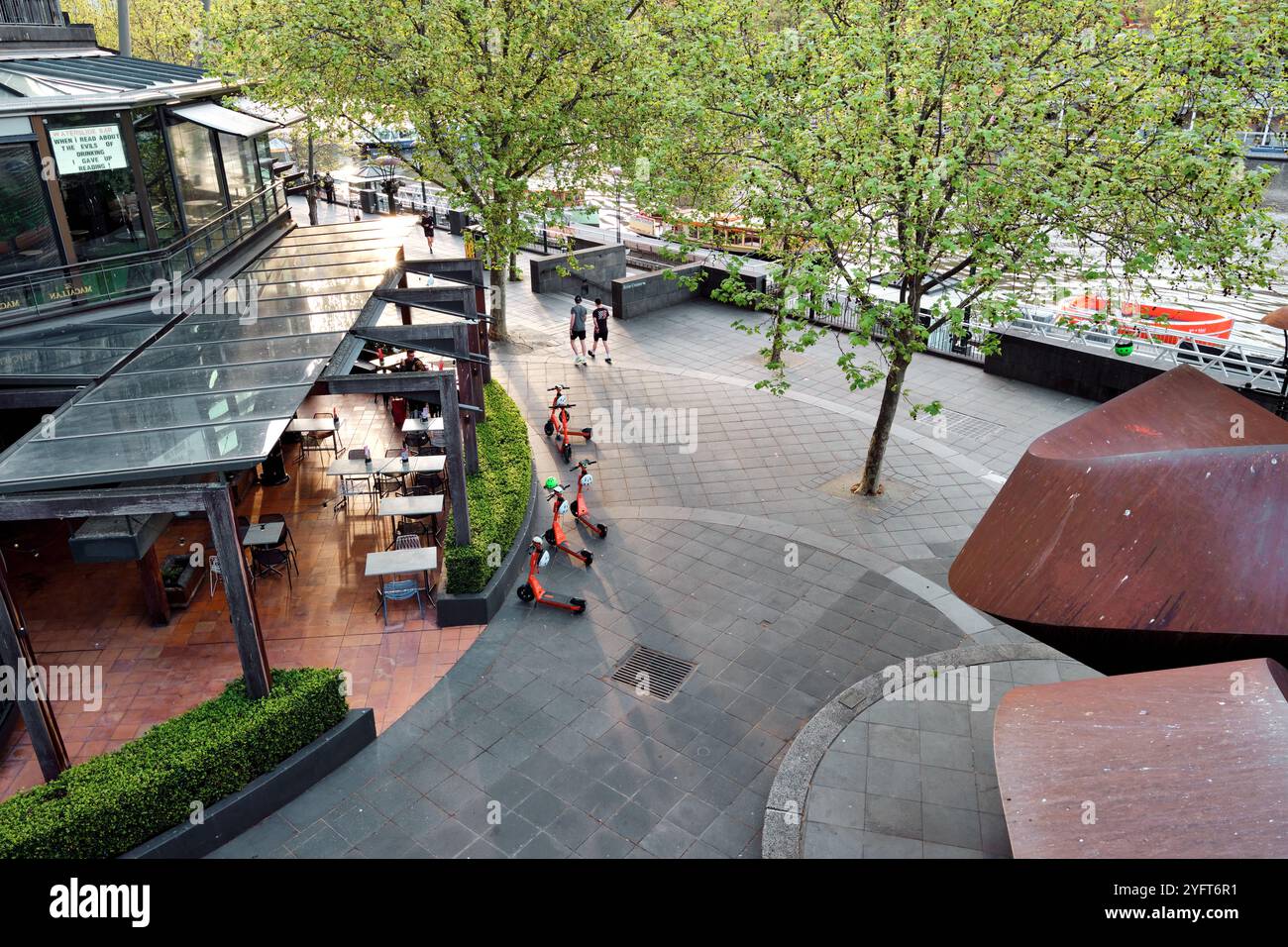 Blick nach unten auf die Southbank Promenade im späten Nachmittagslicht einschließlich E-Scooters und der Waterslide Bar, Melbourne, Victoria, Australien. Stockfoto