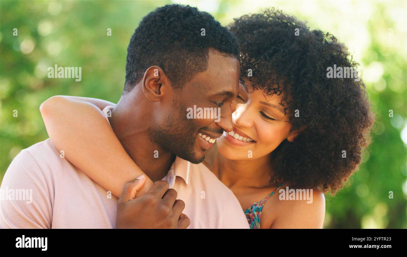 Ein fröhliches Paar teilt einen liebevollen Moment draußen unter der Sonne. Stockfoto
