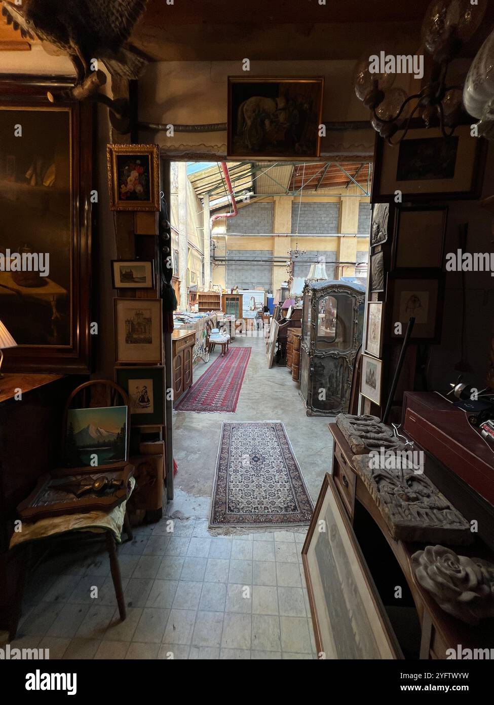 Ein gemütlicher Antiquitätenladen mit Vintage-Artikeln, Möbeln und gerahmten Gemälden, die ein einladendes und nostalgisches Ambiente schaffen - Smartphone-aufgenommenes Stockfoto