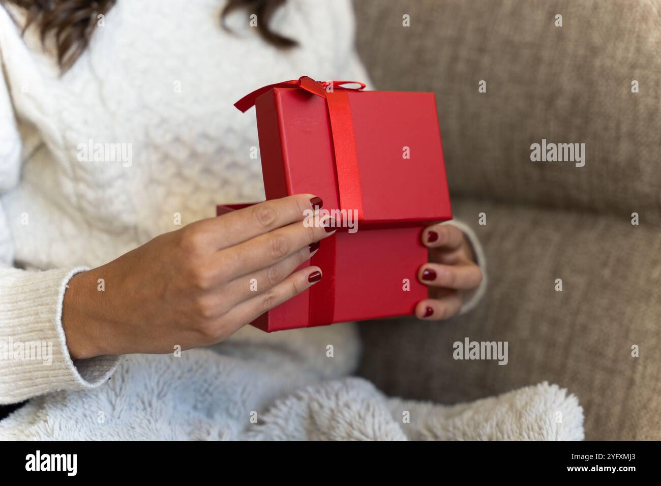 Nicht wiedererkennbares Mädchen, das eine Geschenkbox an Weihnachten oder Valentinstag öffnet Stockfoto