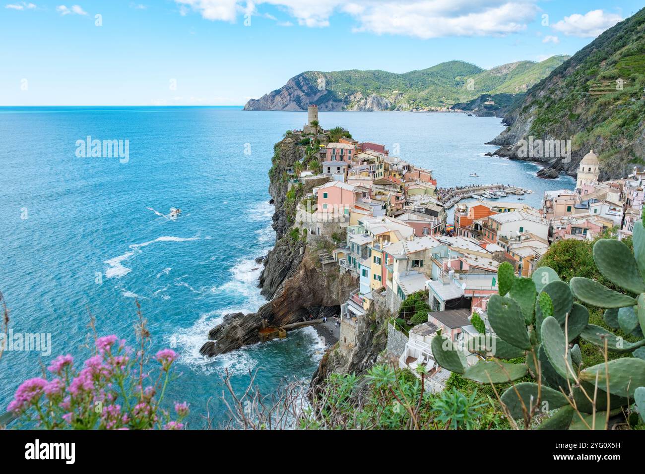 Farbenfrohe Häuser an den felsigen Klippen von Vernazza Italien, während die Wellen sanft am Ufer schlängeln. Die atemberaubende Landschaft von Cinque Terre zeigt die Schönheit der Natur in Italiens Ligurien. Stockfoto