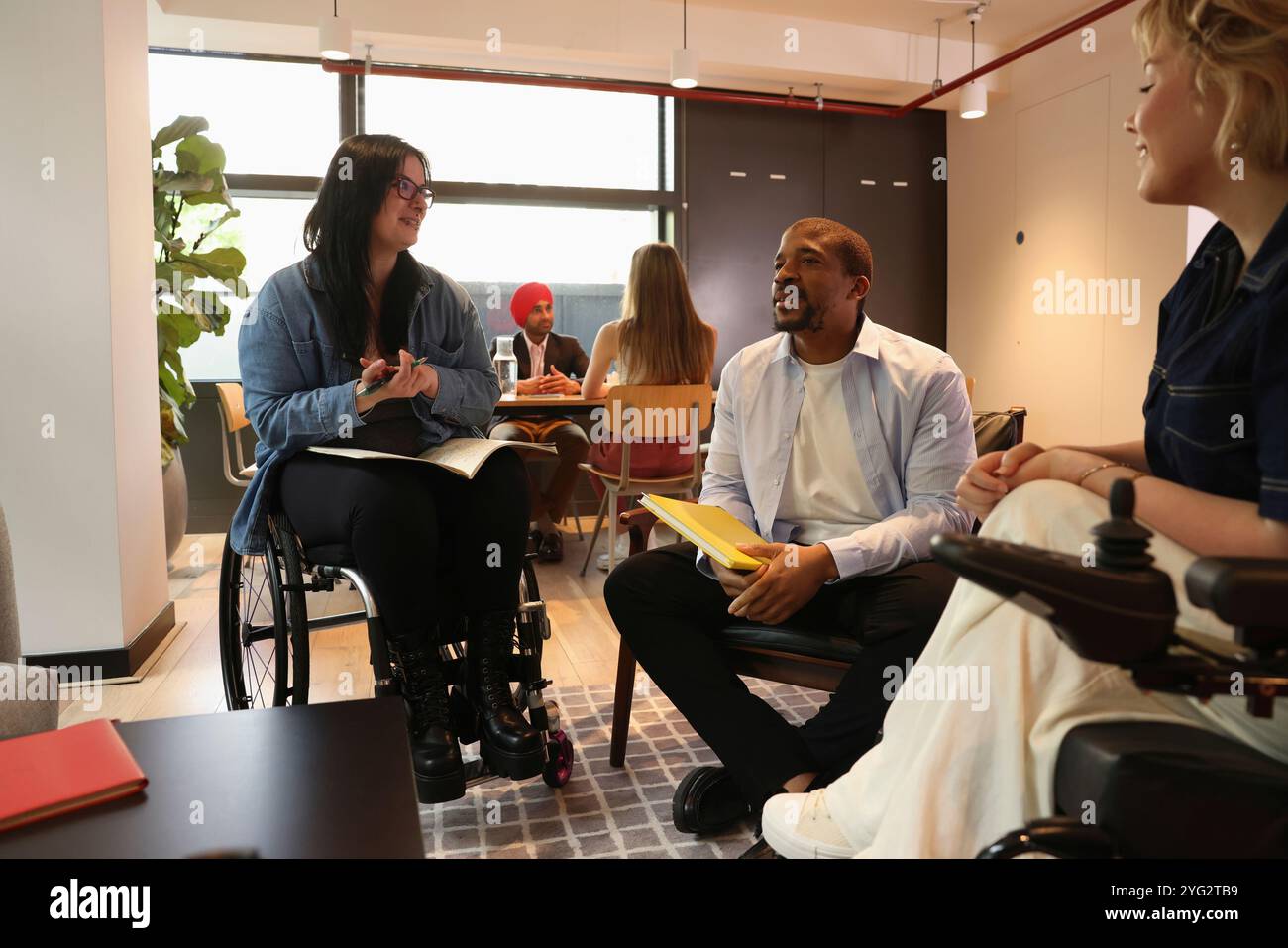 Frauen im Rollstuhl, die an einem Treffen mit Kollegen teilnehmen Stockfoto