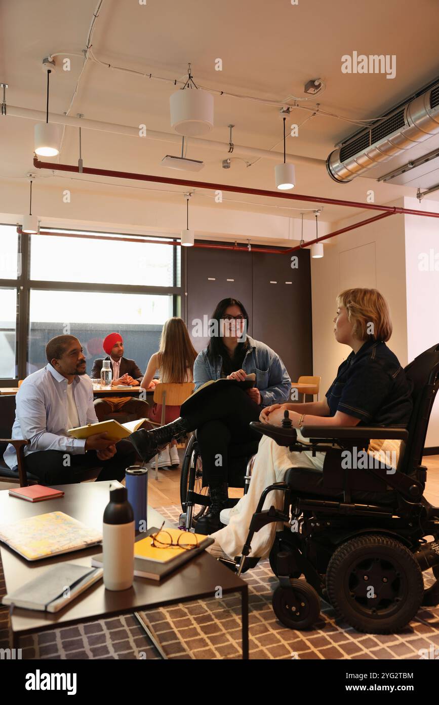 Frauen im Rollstuhl, die an einem Treffen mit Kollegen teilnehmen Stockfoto