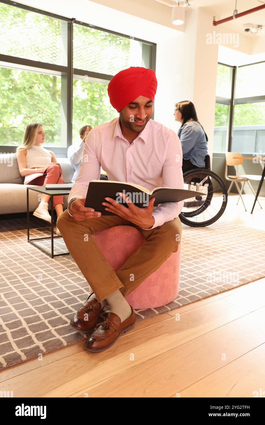 Geschäftsmann trägt Sikh-Turban und liest Dokumente im Büro Stockfoto