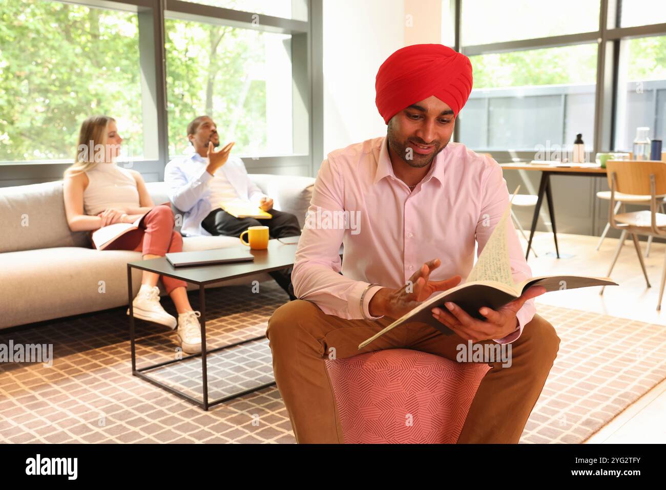 Geschäftsmann trägt Sikh-Turban und liest Dokumente im Büro Stockfoto