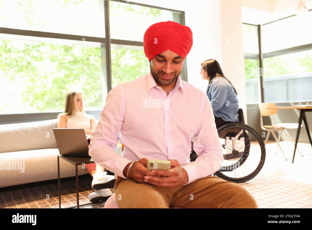 Geschäftsmann mit Sikh-Turban und Telefon im Büro Stockfoto