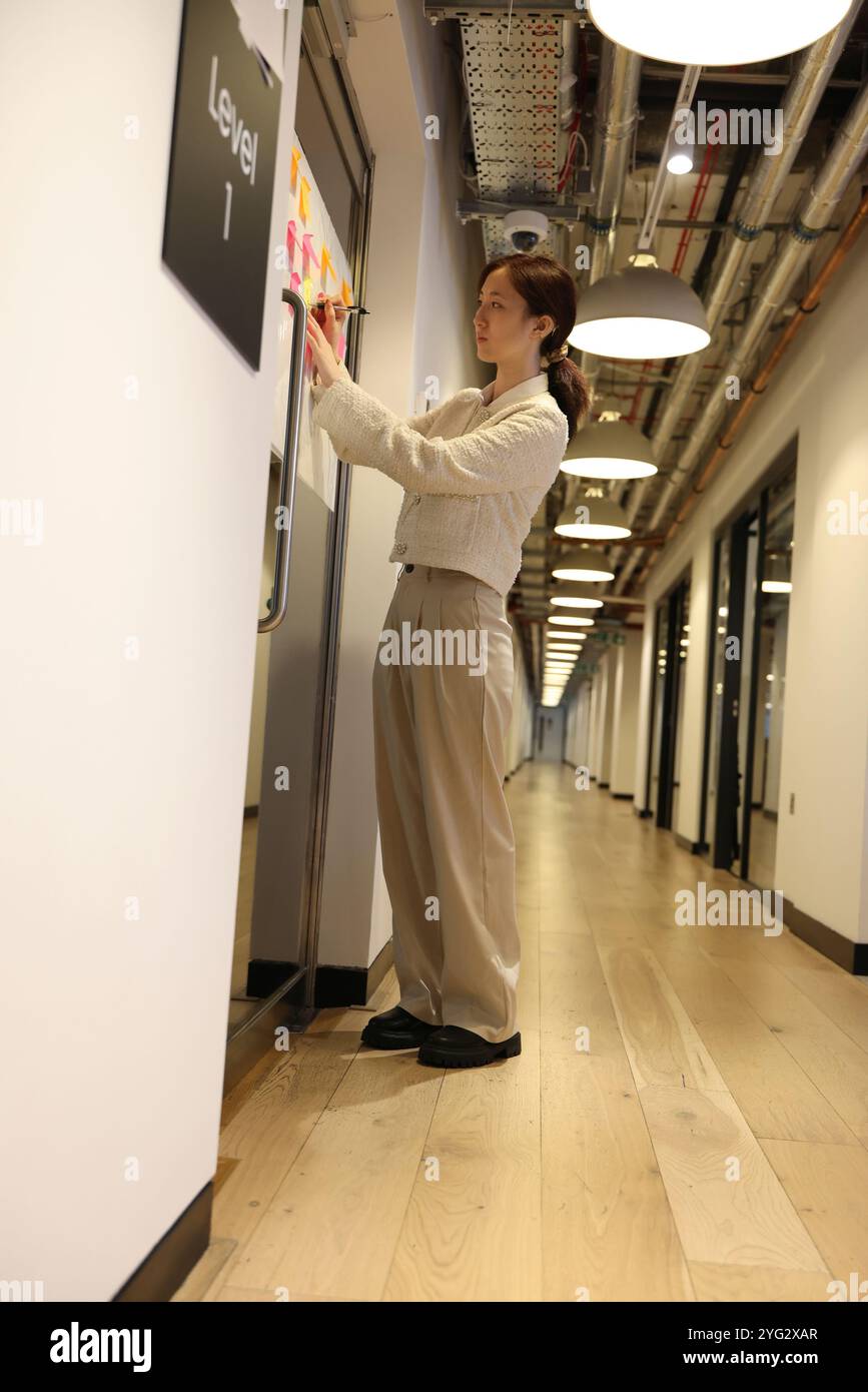 Der Mitarbeiter macht Notizen am Bulletin Board Stockfoto