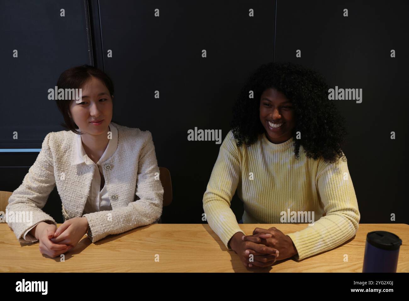 Lächelnde Frauen sitzen im Büro Stockfoto