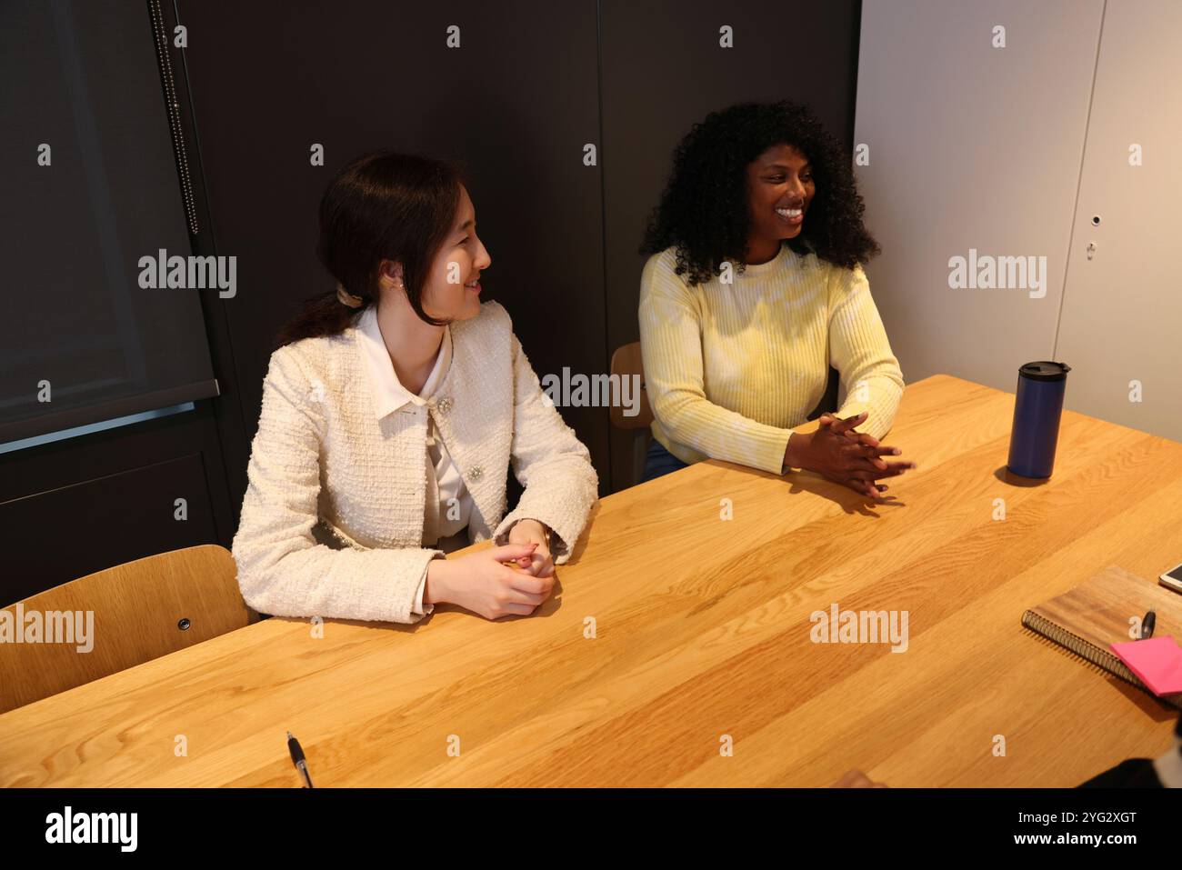 Lächelnde Frauen sitzen im Büro Stockfoto