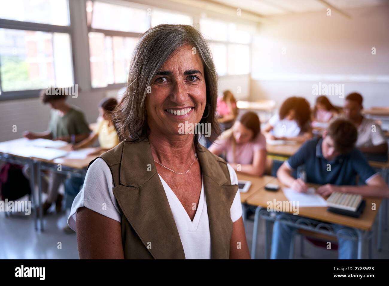 Porträt einer glücklichen, Reifen kaukasischen Lehrerin an der High School, die sich selbstbewusst im Unterricht posiert. Stockfoto