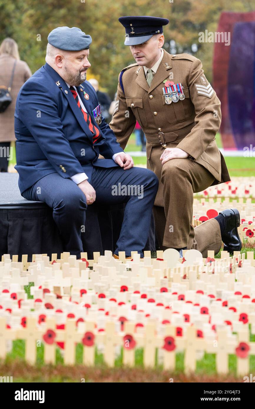 Eröffnung des Gedenkmohnfeldes am National Memorial Arboretum im November 2024. Mohnblumen wurden auf dem Feld platziert, um an die Verstorbenen in den Weltkriegen und Konflikten zu erinnern. Während der Gedenkfeier fanden zwei Mitglieder der Gruppe „Talent in the Ranks“ statt, Lee Wright (ein Gedicht vorlesen) und Michael Lauchlan (ein Lied vorführen). Im Bild halten Michael und Lee für einen Moment der Reflexion inne Stockfoto