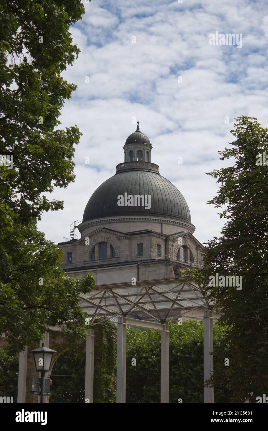 Das Bayerische Staatskanzleramt ist elegant von Bäumen und einem bewölkten Himmel eingerahmt und präsentiert klassische Architektur in einer ruhigen Parklandschaft. Stockfoto