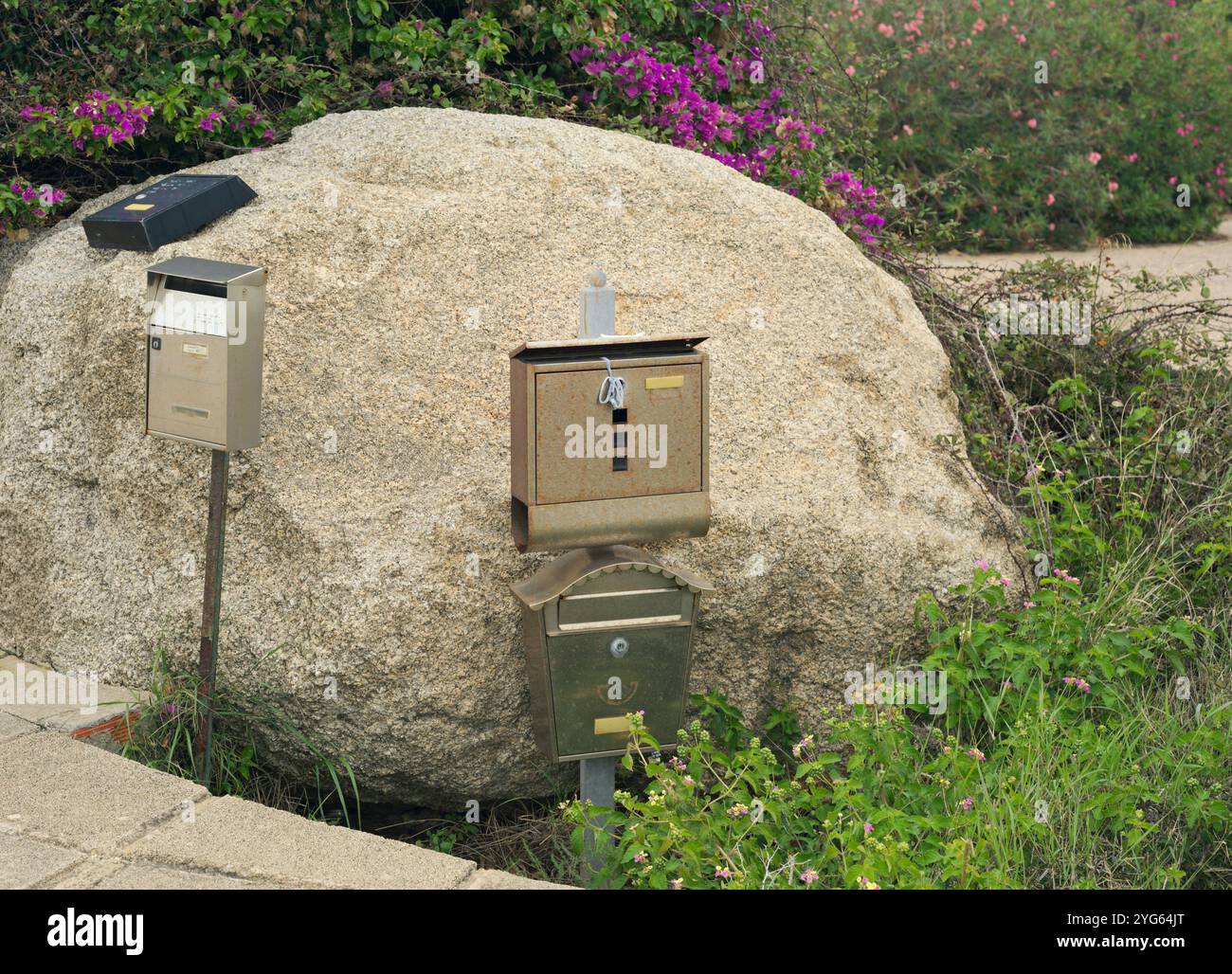 Ländliche Briefkästen auf Felsbrocken zwischen Pflanzen, Sardinien, Italien Stockfoto