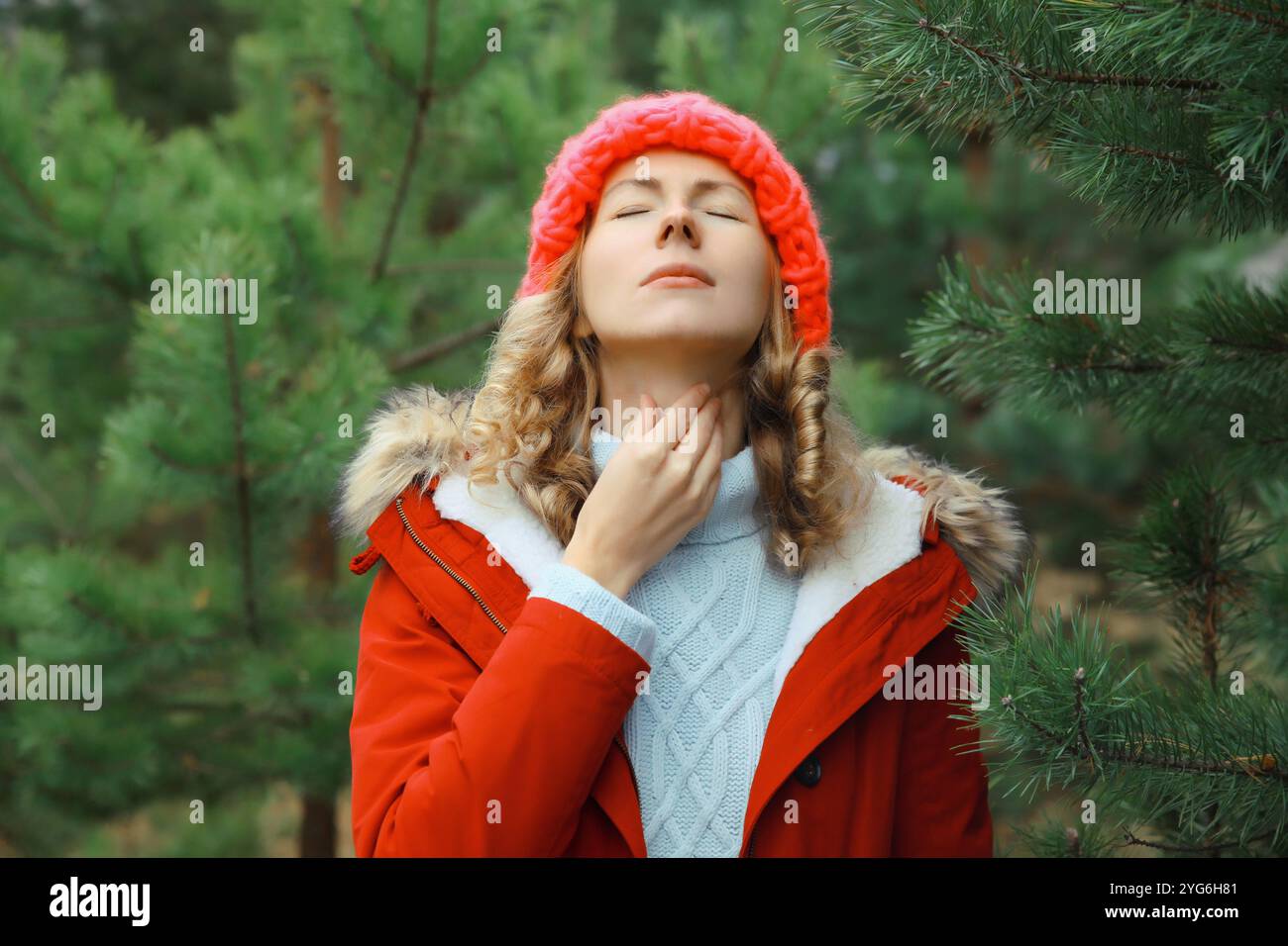 Kranke erschöpfte junge Frau, die an akuten Schmerzen in der Rachengrippe leidet, berührt ihren Hals mit der Hand, sie fühlt sich im Winter Park schlecht Stockfoto