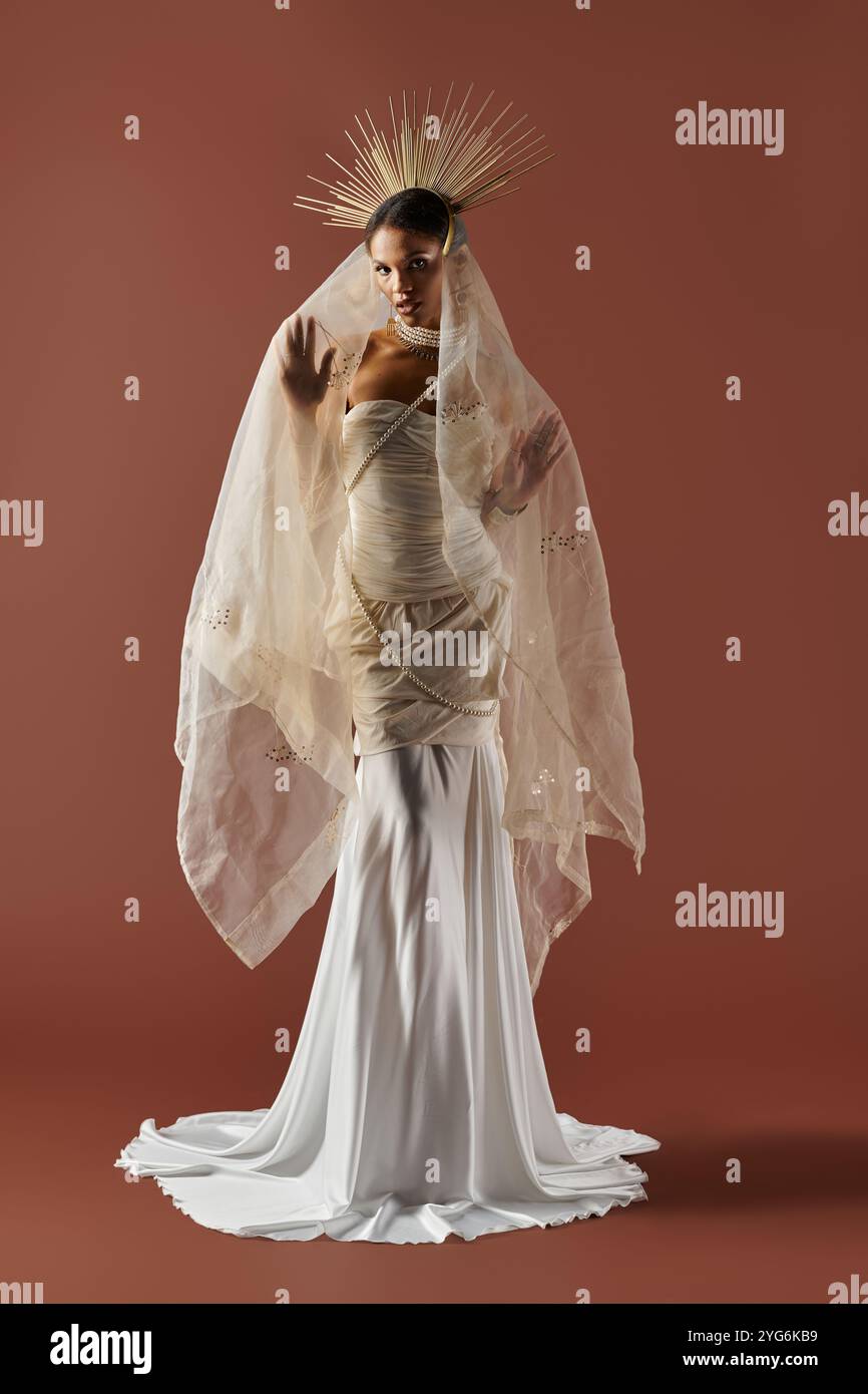 Eine elegante schwarze Frau posiert anmutig in einem fließenden weißen Kleid und Perlen vor einem warmen Hintergrund. Stockfoto