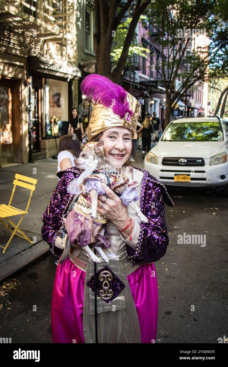Ältere asiatische Frau in schickem Kleid mit kostümiertem Hund in Tompkins Square Halloween Dog Parade 2024 manhattan New york City USA Stockfoto