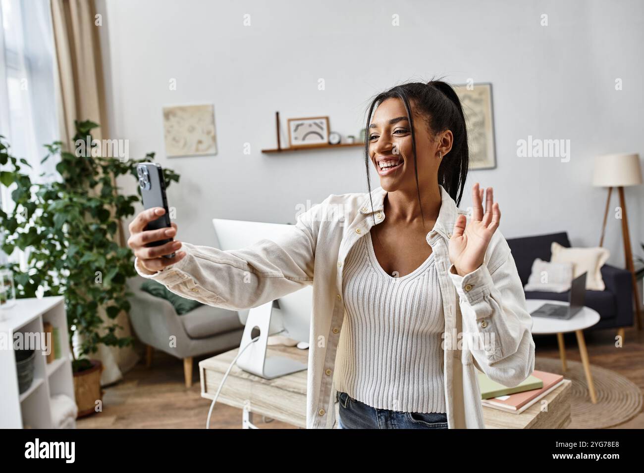 Eine fröhliche junge Frau lernt gerne von zu Hause aus und verbindet sich über ihr Gerät. Stockfoto