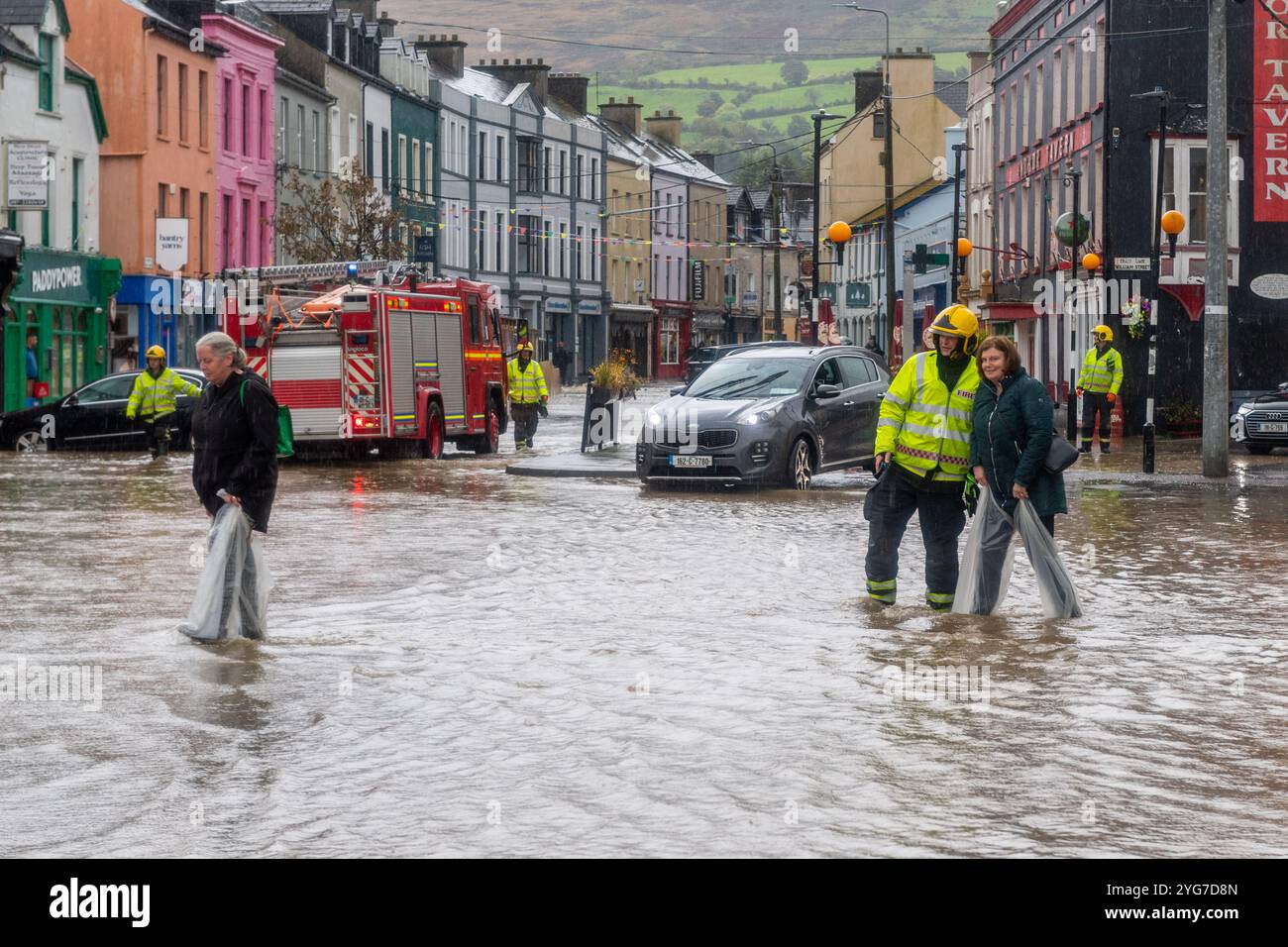 Ein Feuerwehrmann begleitet eine Frau bei Überschwemmungen in Bantry, West Cork, Irland. Stockfoto