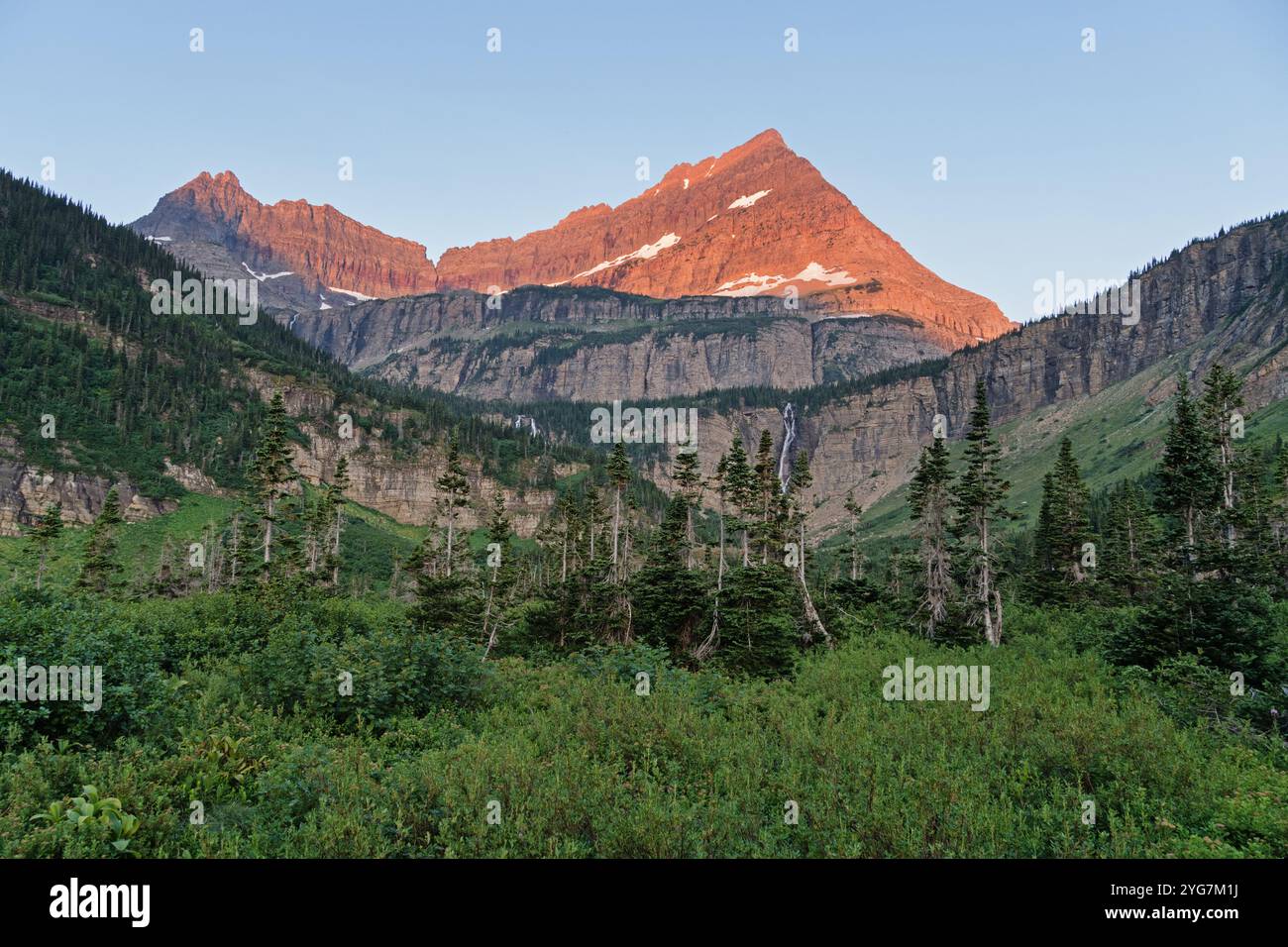 Erstes Morgenlicht auf dem Cathedral Peak über den Atsina Falls im Glacier National Park in Montana Stockfoto