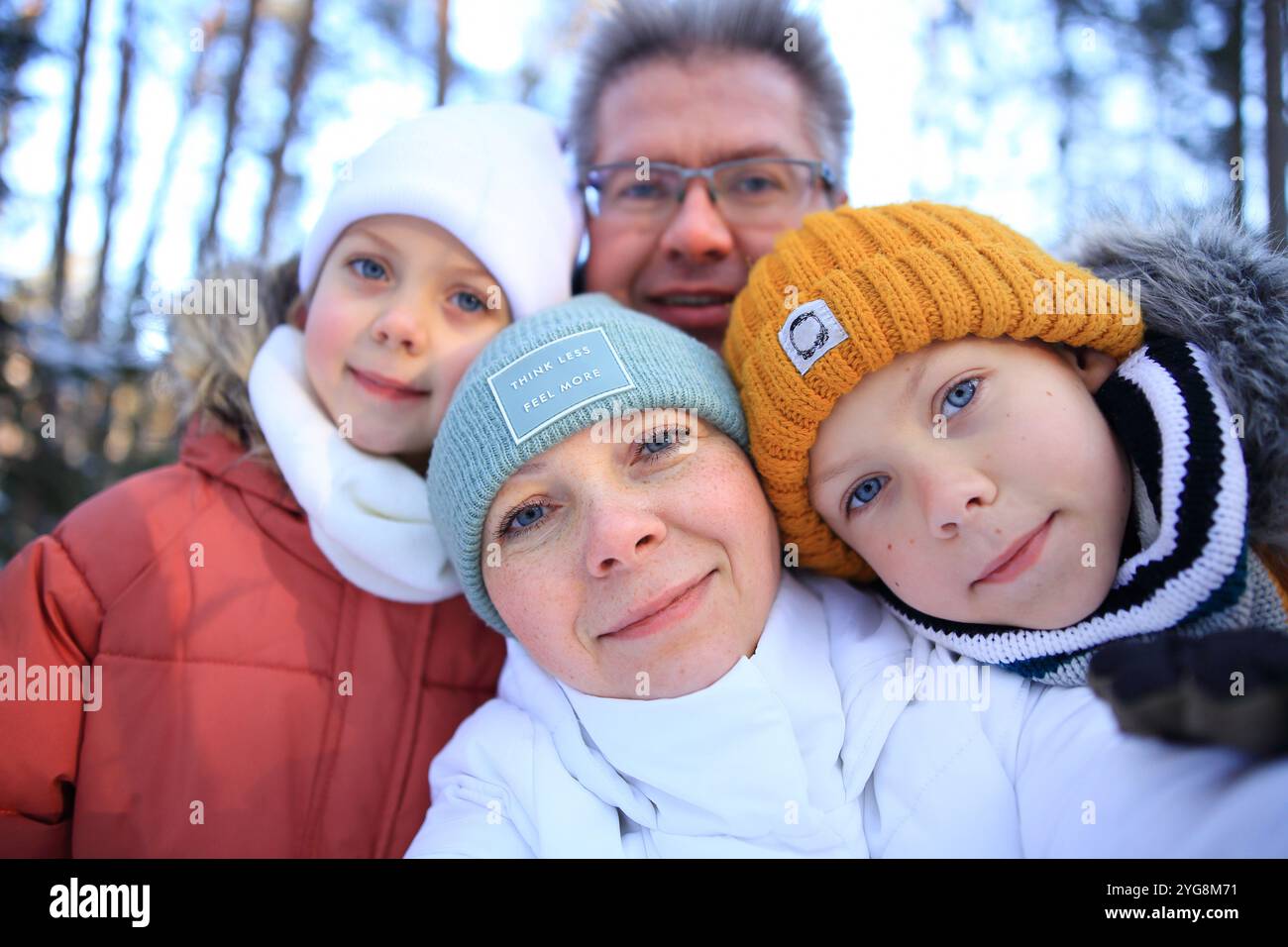 Eine fröhliche Mutter, Vater, Tochter und Sohn posieren zusammen für ein Selfie in einer malerischen Winterlandschaft. Umgeben von schneebedeckten Bäumen und einem ruhigen sno Stockfoto