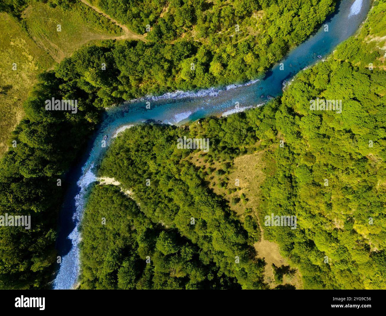 Aus der Vogelperspektive auf einen ruhigen, sich windenden Fluss, der durch üppige grüne Waldlandschaft fließt, perfekt für Naturliebhaber und Abenteurer. Stockfoto