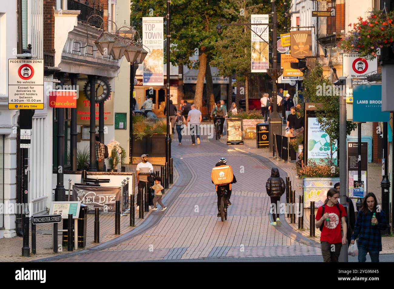 Shopper spazieren auf der Fußgängerzone Winchester Street (auch bekannt als Spitze der Stadt) in der späten Nachmittagssonne in Basingstoke, Großbritannien. Konzept: Wirtschaft Stockfoto