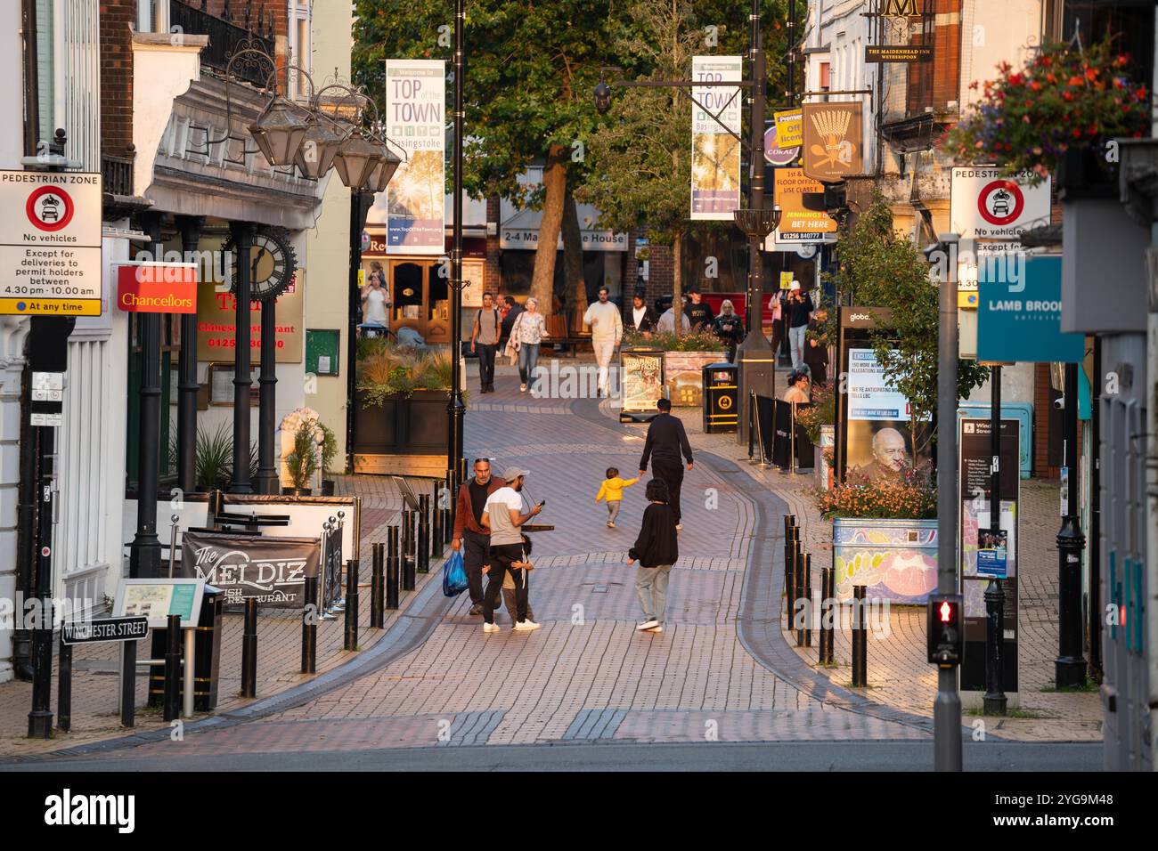 Shopper spazieren auf der Fußgängerzone Winchester Street (auch bekannt als Spitze der Stadt) in der späten Nachmittagssonne in Basingstoke, Großbritannien. Konzept: Wirtschaft Stockfoto