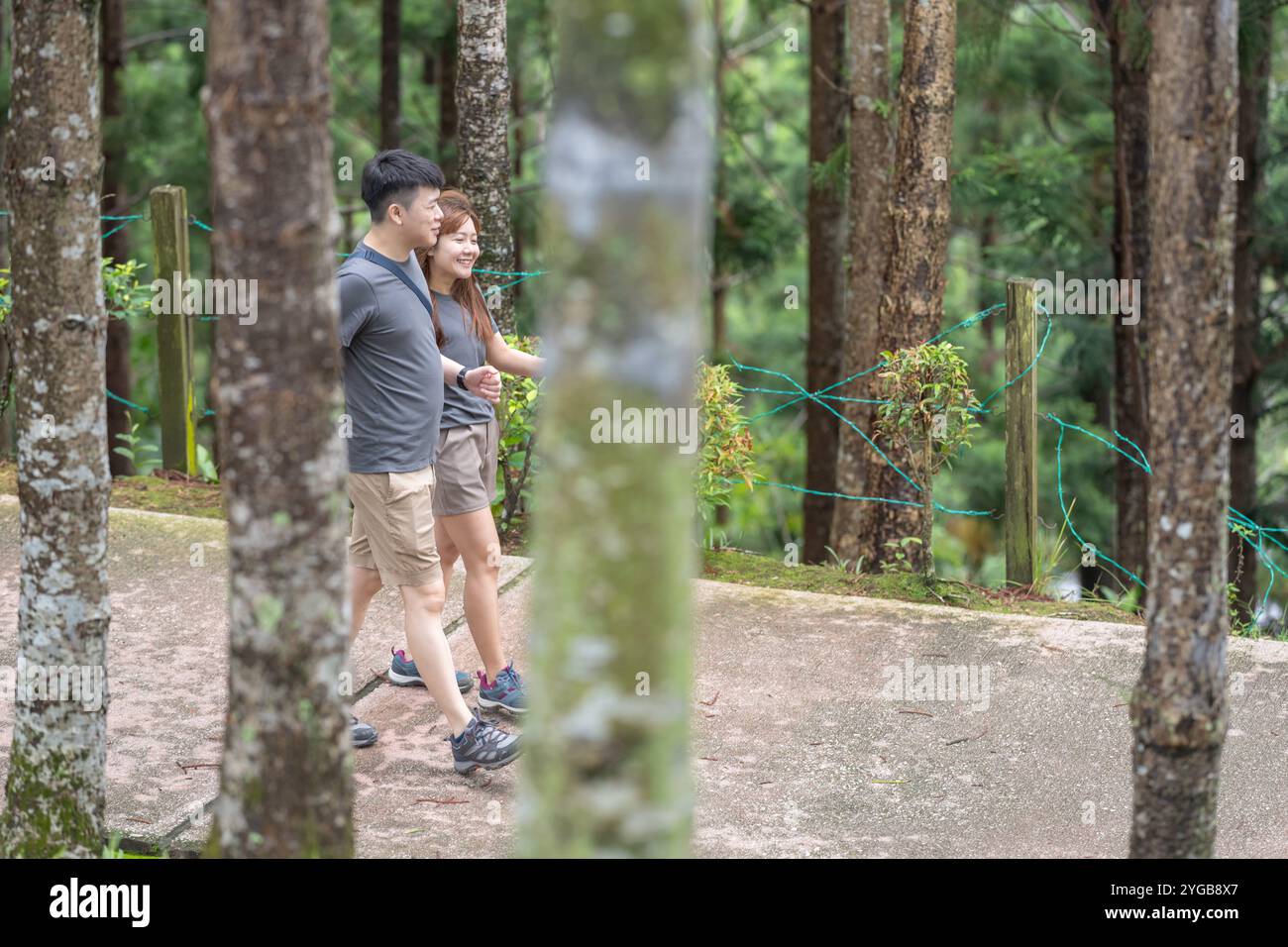 Ein chinesisch-malaysisches Paar in den 30ern spaziert zusammen in einem grünen Park mit reichlich Wasser in Kuala Lumpur, Malaysia, an einem sonnigen Tag im Juni 2024. Stockfoto