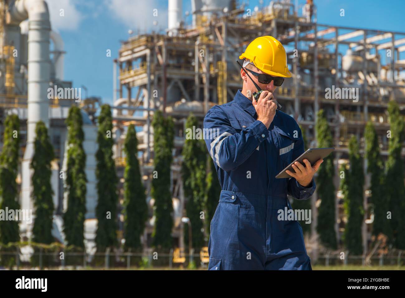 Arbeiter in der Erdölindustrie, der im Freien arbeitet. Der Leiter der Raffinerieöl- und Gasdienstleister führt die Instandhaltung komplexer Gasrohrgebäude mit Tablett durch Stockfoto