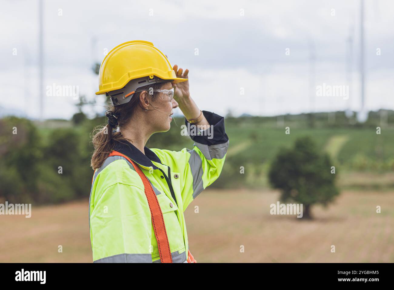 Porträt Intelligente Erwachsene Ingenieurinnen Expertin schaut weg auf Wind Turbines saubere Stromerzeuger Feld Hintergrund. Stockfoto