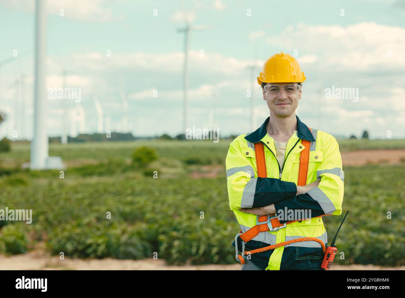 Intelligenter, zuversichtlicher Techniker, männlicher Arbeiter, der bei Windturbinen arbeitet, auf dem Feld für Windkraftanlagen im Freien. Stockfoto